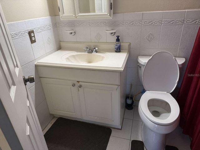 bathroom with vanity, toilet, tile patterned flooring, and tile walls