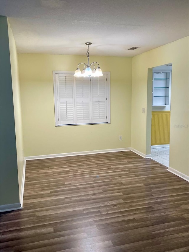 unfurnished dining area featuring a notable chandelier and dark wood-type flooring