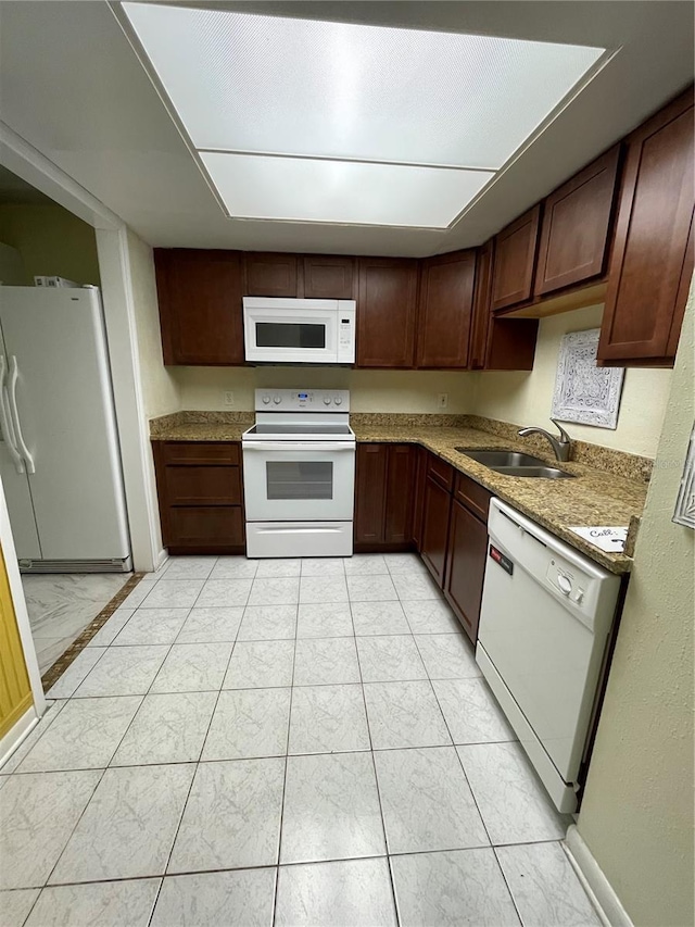 kitchen featuring white appliances, stone countertops, sink, and dark brown cabinetry