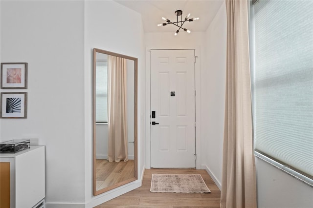 doorway to outside featuring light hardwood / wood-style flooring and a notable chandelier