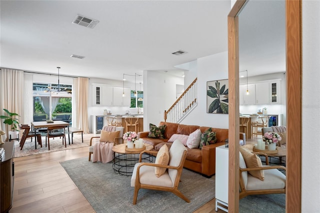 living room featuring wine cooler, a chandelier, and light wood-type flooring