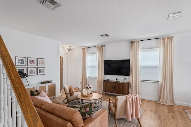 living room featuring a textured ceiling, light hardwood / wood-style floors, and a healthy amount of sunlight