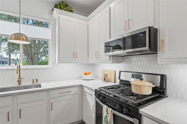 kitchen featuring sink, white cabinetry, backsplash, stainless steel appliances, and decorative light fixtures