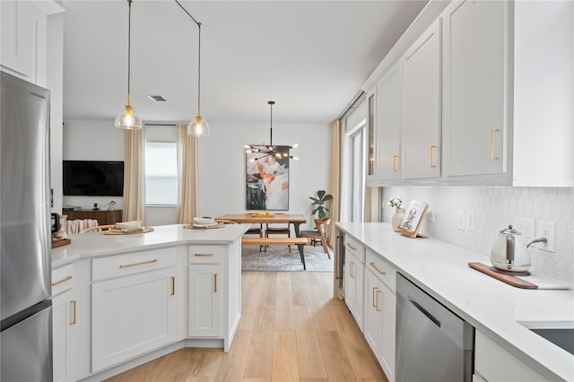 kitchen featuring appliances with stainless steel finishes, decorative light fixtures, and white cabinets