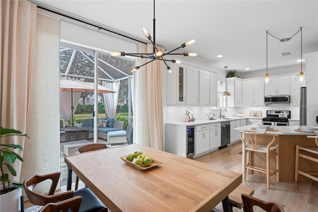 dining space with sink, wine cooler, and light hardwood / wood-style flooring