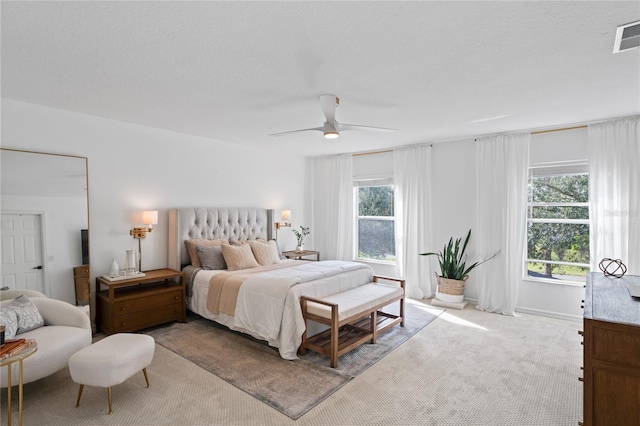 bedroom featuring light carpet, a textured ceiling, and ceiling fan