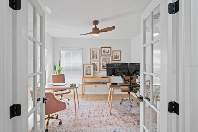 office space with ceiling fan, light hardwood / wood-style flooring, french doors, and a healthy amount of sunlight