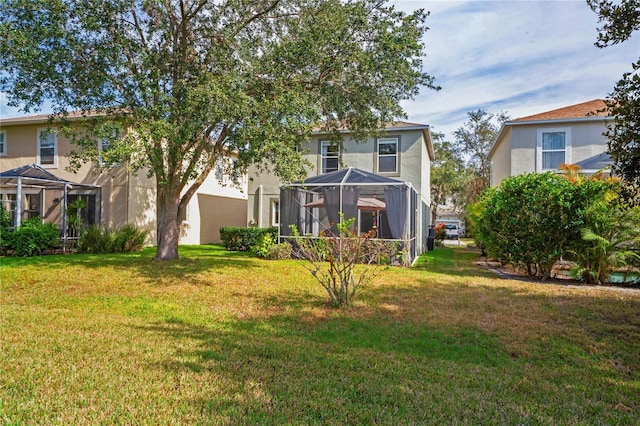 rear view of property featuring a lanai and a lawn