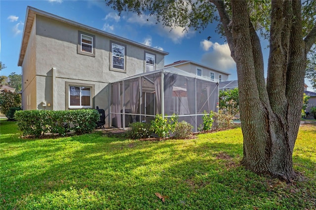 back of property featuring a lanai and a lawn