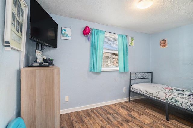 bedroom with dark hardwood / wood-style flooring and a textured ceiling