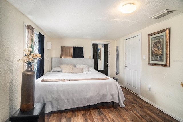 bedroom with dark hardwood / wood-style floors and a textured ceiling