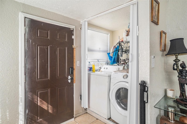 laundry room with light tile patterned flooring, a textured ceiling, and washer and clothes dryer