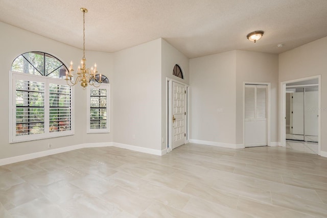 spare room with a chandelier and a textured ceiling