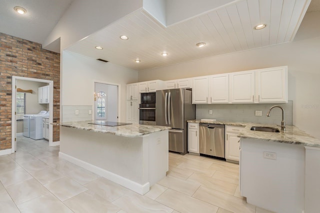 kitchen featuring sink, black appliances, washer and dryer, white cabinets, and kitchen peninsula