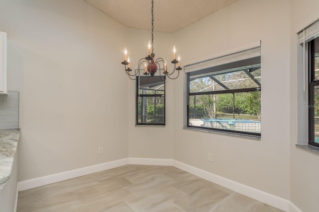 unfurnished dining area featuring a notable chandelier and a textured ceiling