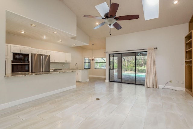 unfurnished living room with sink, ceiling fan with notable chandelier, and high vaulted ceiling