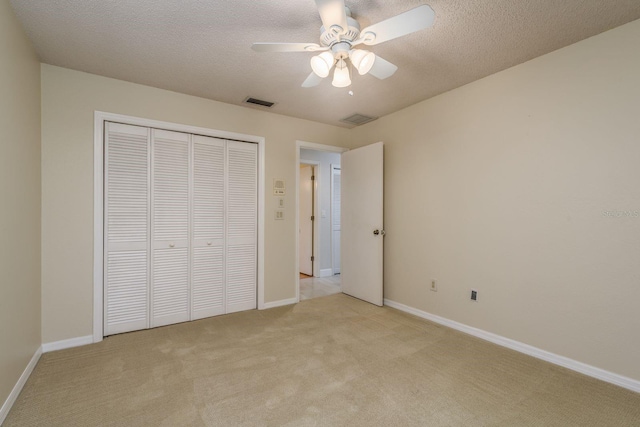 unfurnished bedroom with ceiling fan, a closet, light carpet, and a textured ceiling