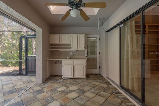 kitchen with sink, white cabinets, and ceiling fan