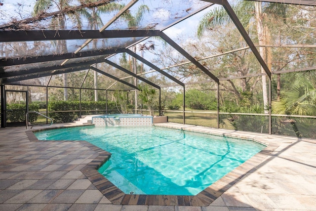 view of swimming pool featuring an in ground hot tub, pool water feature, glass enclosure, and a patio area