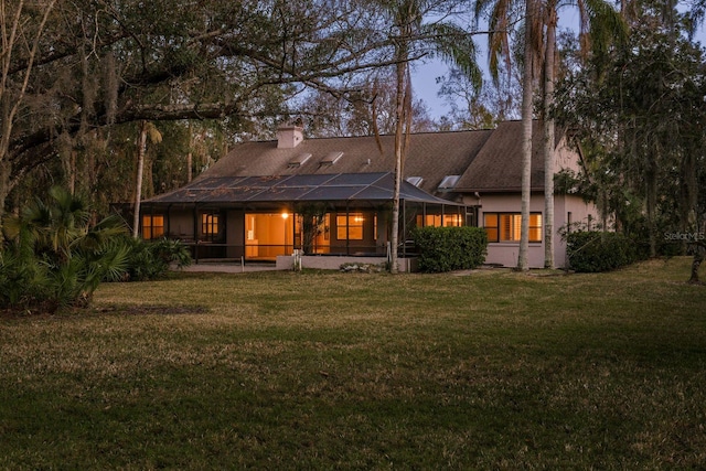 back of property with a yard and glass enclosure