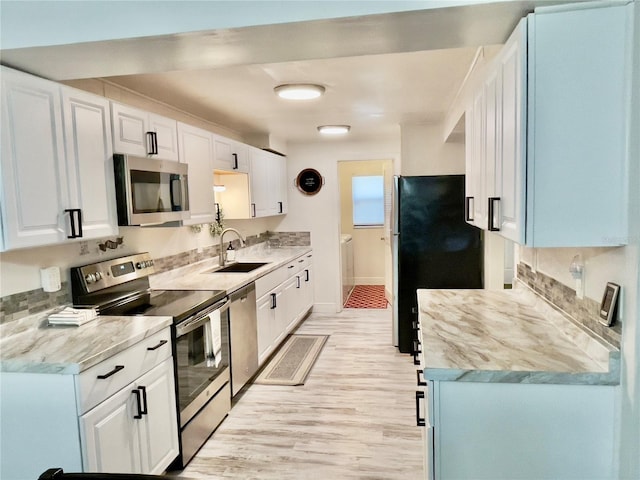 kitchen with white cabinetry, sink, light wood-type flooring, and appliances with stainless steel finishes