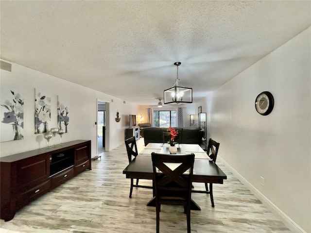 dining room featuring an inviting chandelier, light hardwood / wood-style flooring, and a textured ceiling