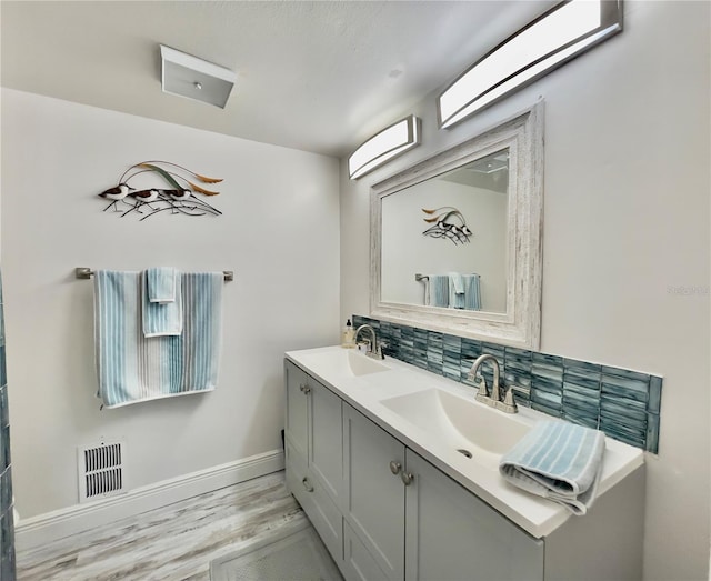 bathroom featuring vanity, wood-type flooring, and decorative backsplash