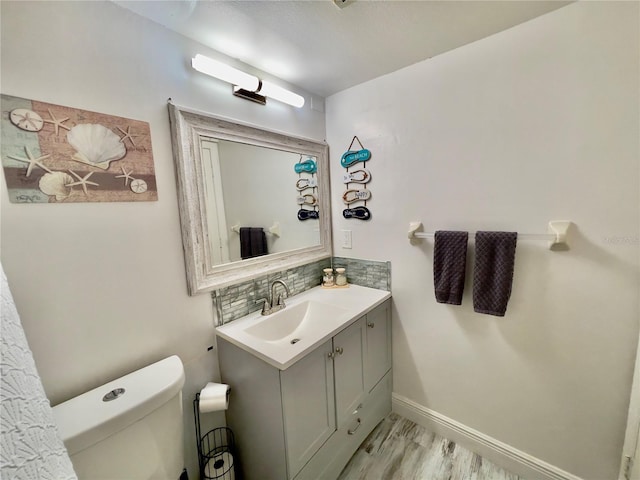 bathroom featuring tasteful backsplash, vanity, hardwood / wood-style flooring, and toilet