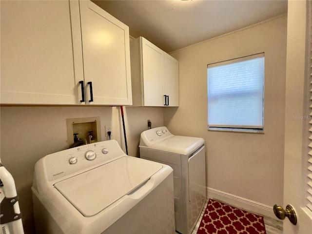 clothes washing area featuring cabinets and separate washer and dryer