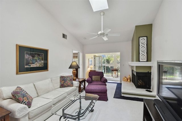 living room with a skylight, high vaulted ceiling, carpet flooring, ceiling fan, and a fireplace