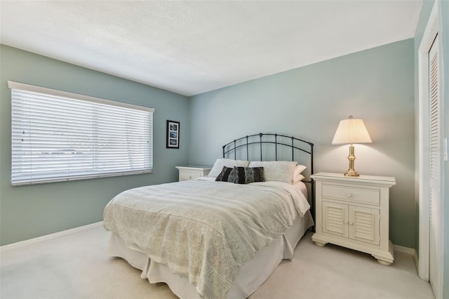 bedroom featuring baseboards, a closet, and light carpet