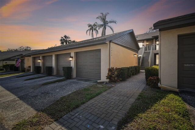 view of side of property featuring stucco siding, a garage, and stairway