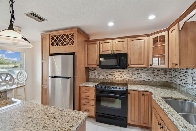 kitchen with visible vents, black appliances, decorative backsplash, a sink, and glass insert cabinets