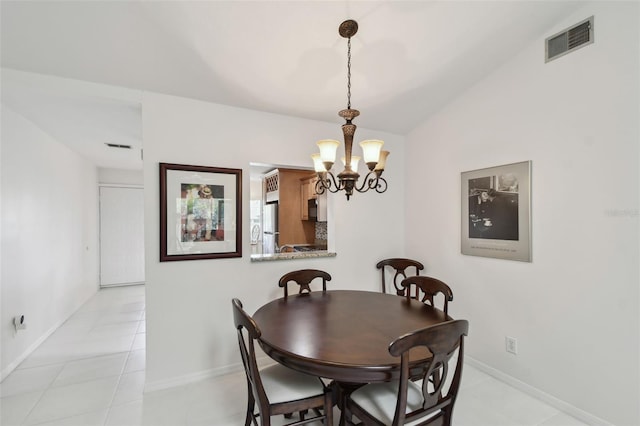 dining area with visible vents, baseboards, a chandelier, vaulted ceiling, and light tile patterned floors