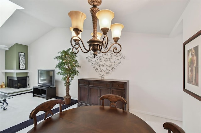 dining area with baseboards, lofted ceiling, a notable chandelier, and a glass covered fireplace