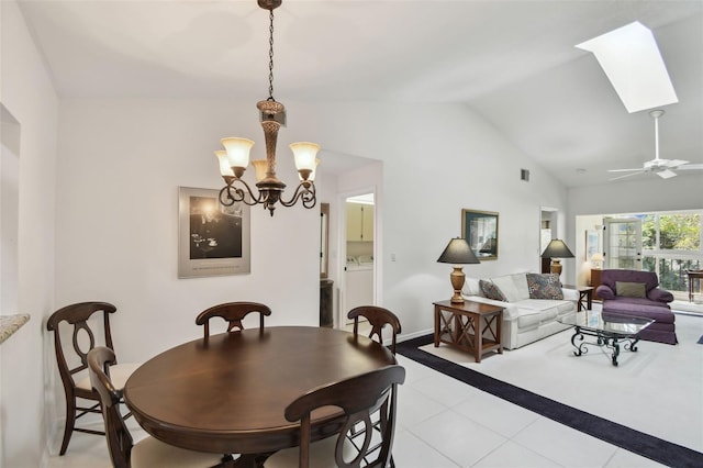 dining space featuring baseboards, an inviting chandelier, washer / dryer, light tile patterned flooring, and lofted ceiling with skylight