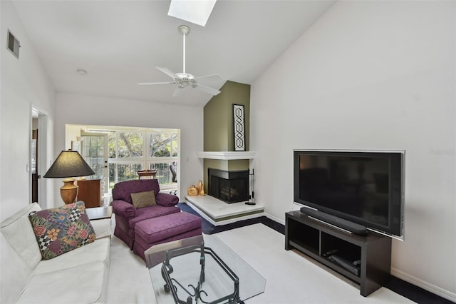 living room featuring lofted ceiling with skylight, visible vents, a fireplace, and baseboards