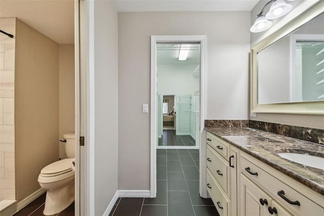 bathroom featuring vanity, toilet, baseboards, and tile patterned flooring