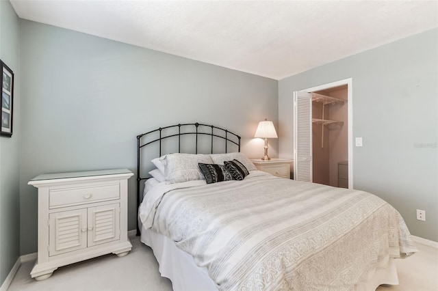 bedroom featuring a closet, baseboards, light carpet, and a walk in closet