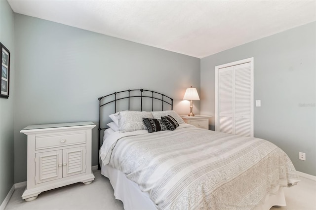 bedroom featuring a closet, light carpet, and baseboards