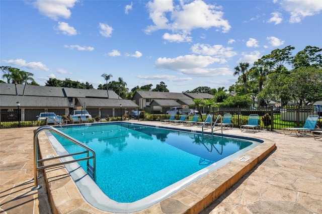 pool featuring a patio area, fence, and a residential view