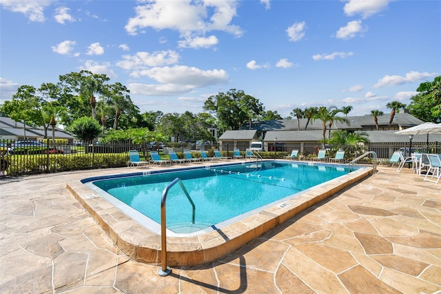 community pool with a patio area and fence