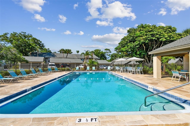 community pool with a patio area and fence