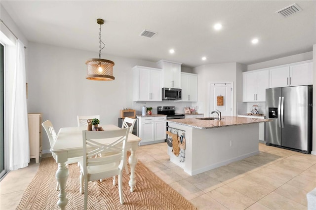 kitchen featuring sink, appliances with stainless steel finishes, white cabinetry, light stone countertops, and an island with sink