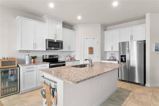 kitchen with appliances with stainless steel finishes, white cabinetry, an island with sink, sink, and wine cooler