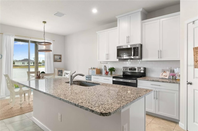 kitchen with white cabinetry, stainless steel appliances, sink, and a center island with sink