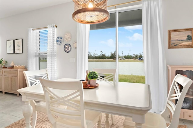 dining space with a water view and light tile patterned floors