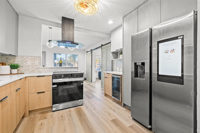 kitchen with a barn door, island range hood, electric range oven, stainless steel fridge, and beverage cooler