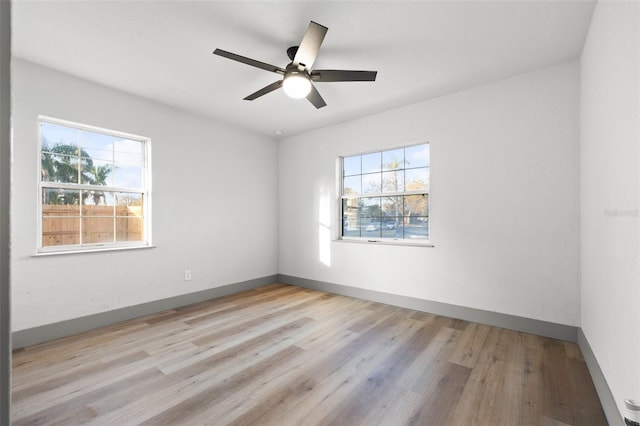 empty room with ceiling fan, a healthy amount of sunlight, and light hardwood / wood-style flooring