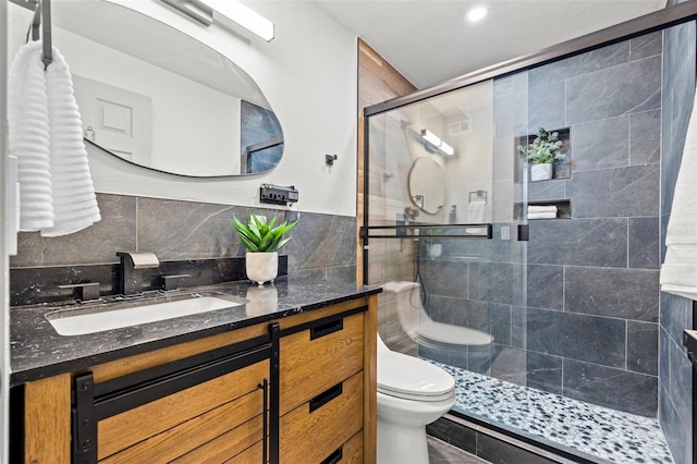 bathroom featuring vanity, a shower with shower door, tile walls, and toilet